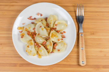 Cooked filled dumplings flavored with fried bacon and onion, fork