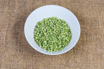 Green split peas in bowl on a fabric surface