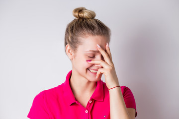 Beautiful woman with clean skin, natural makeup laughs, smiles and covers his face with his hand on a white background