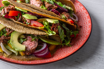 Tacos with grilled meat, avocado, fresh salsa sauce and limes over rustic background. Healthy low carb and low fat lunch or food for company. Dieting and weight loss concept