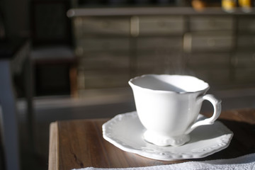 Steamy coffee cup made of white porcelain on a wooden table