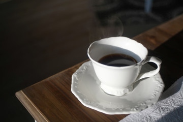 Steamy coffee cup made of white porcelain on a wooden table