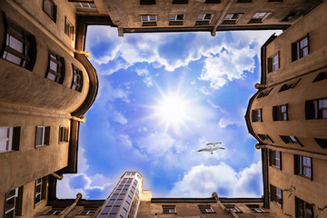 Old town house. Birds fly over the house. Bottom view. View of the sunny sky. Well, architektura old yards.