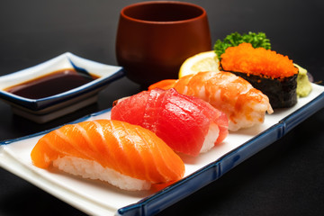 Sushi salmon & tuna sushi shrimp and wasabi on the white plate. on the black table