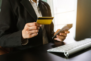 businesswoman hand using smart phone, tablet payments and holding credit card online shopping, omni channel, digital tablet docking keyboard computer at office in sun light