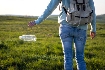 Irresponsible tourist throwing away plastic bottle in nature. Environmental damage