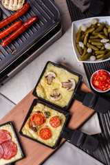 young woman is preparing a traditional Swiss cheese raclette