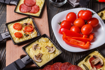 young woman is preparing a traditional Swiss cheese raclette
