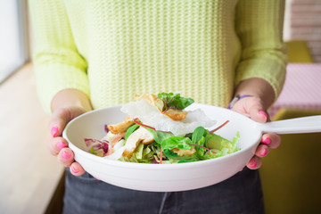 Woman hands holds big white plate with italian salad in a restaurant