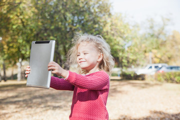 Little girl playing with a tablet in the Park