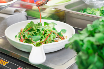 An Italian chef prepares a salad in a restaurant with fresh vegetables, tasty and healthy food for everyone