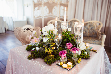 A gentle and romantic decoration from the moss and fresh flowers of the evening table in a beautiful light restaurant