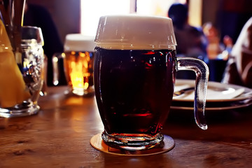mug of dark beer in the interior of  pub / pint of beer with foam on a served table in  beer restaurant in Czech Republic