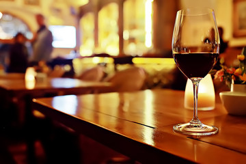 red wine glass serving / romantic dinner in the interior of the restaurant, a table served with a glass of grapes wine
