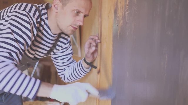 Worker paints a wooden attic. Wood surface treatment. Closeup portrait