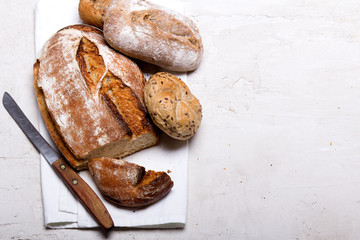 Tasty dark bread and buns  on white background, copy space. Bakery products, wholemeal bread and brown whole wheat buns