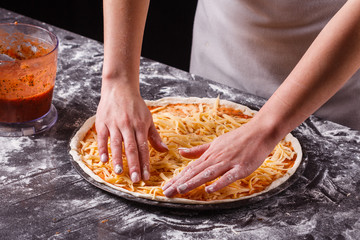 young woman in a gray aprong prepares a pepperoni pizza