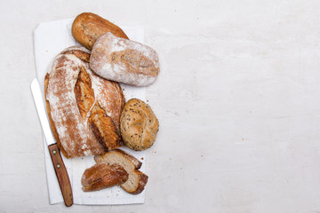 Tasty dark bread and buns  on white background, copy space. Bakery products, wholemeal bread and brown whole wheat buns