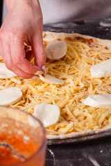 young woman in a gray aprong prepares a pizza margarita
