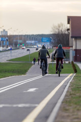 Two cyclists take a bike ride on the city bike path. Spring city evening landscape. Concept: healthy lifestyle.
