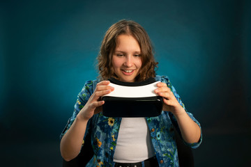 dark-haired girl took off or is going to wear virtual reality glasses with a joyfully surprised facial expression, blue gradient .