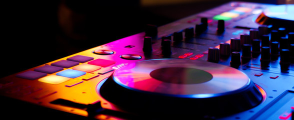DJ controller colorful buttons live show at night club playing edm dance music in neon light