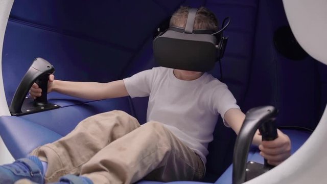 Little boy playing virtual reality in a moving interactive chair