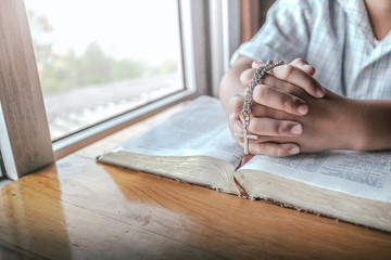 Obraz premium Close up silver cross with hands holding and praying on holy bible. religion concept.