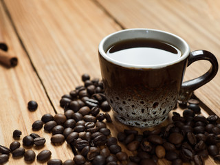 A small Cup of coffee on a wooden table with coffee beans and copyspace