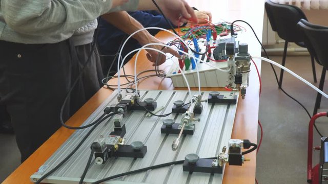 Engineers connect wires control panel with a small test bench for experiments