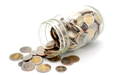 New Thai Baht coins spilling from a glass jar, isolated on white background. Business and finance concept.