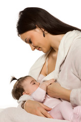 A happy young mother is breastfeeding her baby daughter on a white background