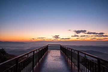 Fototapeta na wymiar rising sun in the morning on top of the hill with wooden pathway ahead to sunrise.Success concept