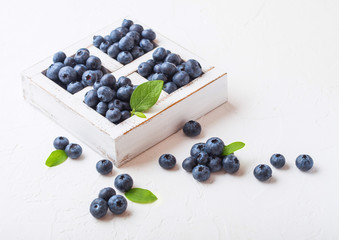 Fresh raw organic blueberries with leaf in vintage wooden box on stone kitchen background. Macro