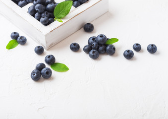Naklejka na ściany i meble Fresh raw organic blueberries with leaf in vintage wooden box on stone kitchen background. Macro
