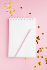Notebook, white sheet, pencil. Pink background