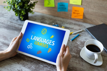 Tablet with languages courses text and icons on screen. English learning online. Education concept.