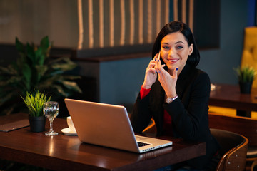 Young business woman talking on the phone in a cafe with a laptop in front of her