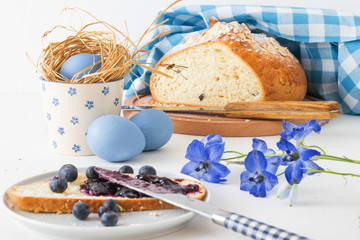 Fototapeta na wymiar Easter breakfast or brunch table in blue style, embellished with Easter symbols, traditional Czech Easter pastry Mazanec, Pomlazka and eggs.