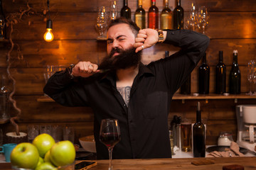 Bearded barman being funny with his beard behind the counter.