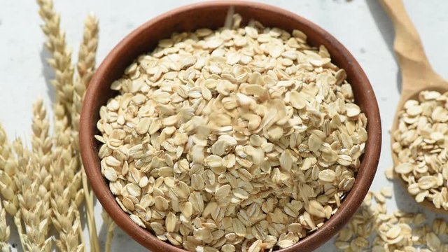 Slow motion of rolled oats or oat flakes falling into bowl. Healthy food, clean eating, healthy lifestyle concept