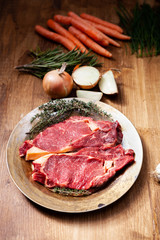 Raw beef stake with herbs and fresh vegetables ready to be grilled