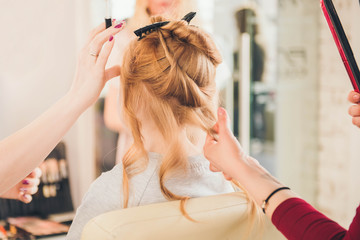Fototapeta premium Сreating hairstyle. Children's hairdressing salon. Hairdresser curling hair for little girl. Make up.