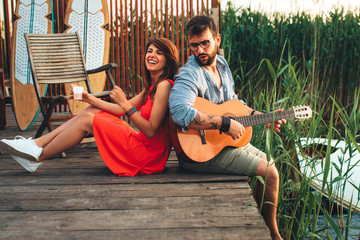 Man and woman singing and playing guitar by the river