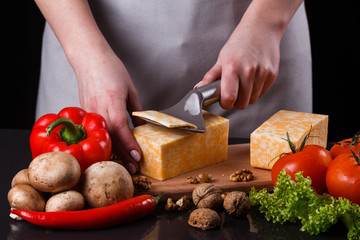 young woman slicing cheese in a gray apron