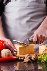 young woman slicing cheese in a gray apron