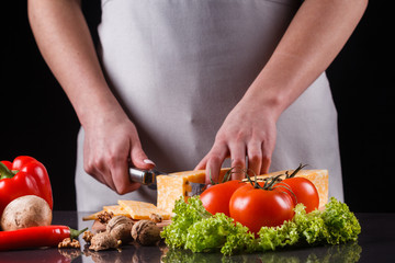 young woman slicing cheese in a gray apron