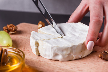 young woman slicing cheese in a gray apron