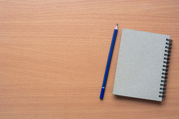 Notepad with pencil on wood board background.using wallpaper for