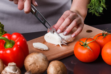 young woman slicing cheese in a gray apron